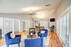 A spacious, brightly lit lounge with blue chairs and wooden flooring.