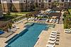 Aerial view of a modern apartment complex pool area with lounge chairs and cabanas.