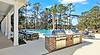A scenic poolside area with BBQ grills and lounge chairs surrounded by trees.