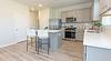 Modern kitchen with gray cabinets, stainless steel appliances, and a countertop seating area.