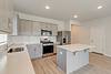 Modern kitchen with gray cabinets, stainless appliances, and an island.