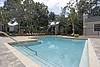 A serene pool area surrounded by trees and lounge chairs, ideal for relaxation.