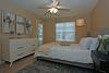 A cozy, well-decorated bedroom featuring a bed, dresser, and natural light.