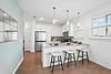 A modern kitchen with gray countertops, white cabinets, and bar stools.