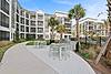 A modern outdoor area featuring tables, palm trees, and a grilling station in an apartment complex.