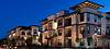 Modern apartment complex at twilight with lit balconies and street lights.