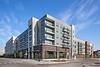 Modern apartment complex showcasing balconies and storefronts under a clear blue sky.