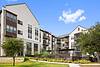 Modern apartment complex with landscaped grounds and blue sky.
