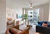 Modern apartment living room with a view of a balcony and a bedroom in the background.