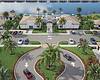 A beautifully landscaped community entrance with palm trees and a circular drive.