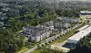 Aerial view of a modern apartment complex surrounded by greenery and nearby commercial areas.