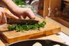 person cutting herbs on wood chopping block