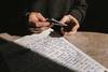 pair of hands with small book and sheet of lyrics on table