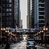 Downtown with tall buildings, train, cars, and pedestrian