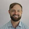 grinning man with beard and striped shirt