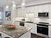 Modern kitchen with granite countertops, stainless steel appliances, and a bowl of fruits.