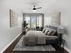 Modern bedroom with a cozy vibe, featuring a bed, armchair, and large windows.