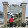 man in sunglasses standing in front of property sign