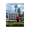 A woman stands next to the Canopy at Seaport Park apartment homes sign.