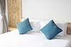 Bed with all white bedding and blue pillows