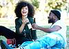 Couple sitting in grass toasting bottles