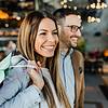 smiling woman with shopping bag over shoulder and smiling man with glasses