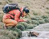 woman bent over water in hiking gear