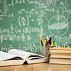books and pencils on table in front of blackboard