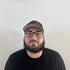 man with glasses, baseball cap, and beard