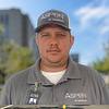 man wearing gray shirt with name tag clipped to collar