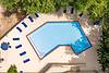 Aerial view of a pool surrounded by lounge chairs and lush greenery.