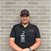 smiling man in black polo shirt and cap with ID badge