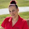 A woman smiling, wearing a red polo shirt with ZRS Management logo.