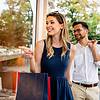 Young man and woman holding hands, smiling and carrying shopping bags.