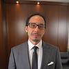 man with short hair, glasses, and grey suit