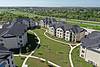 Aerial view of a residential complex with green lawns and pathways near a highway.