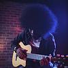 A musician playing an acoustic guitar under stage lights.