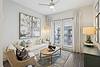 A cozy living room featuring a sofa, artwork, and balcony access.