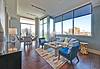 Modern living room with large windows, stylish furniture, and city views.