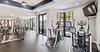 A bright, modern gym with various exercise equipment and large windows for natural light.