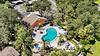 A serene pool surrounded by lush greenery and colorful seating under a blue sky.