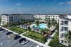 Modern apartment complex with a pool and palm trees.