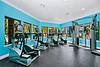 A bright fitness room with exercise machines and large windows letting in natural light.