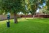 A grassy area with trees and a dog waste station in a fenced yard.