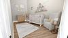 A cozy nursery with a crib, armchair, dresser, and wall decor.