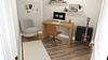 A modern workspace featuring a wooden desk, a computer, a chair, and a guitar.