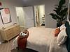 A stylish bedroom with a cozy bed, modern decor, and a plant, creating a warm atmosphere.