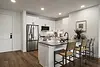 Modern kitchen with stainless steel appliances and bar stools.