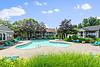 A sunny outdoor pool area surrounded by green trees and lounge chairs.